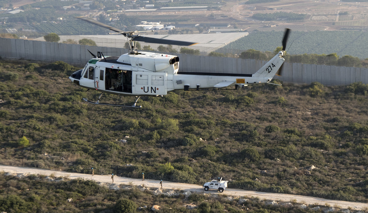 A UNIFIL helicopter hovering above troops.