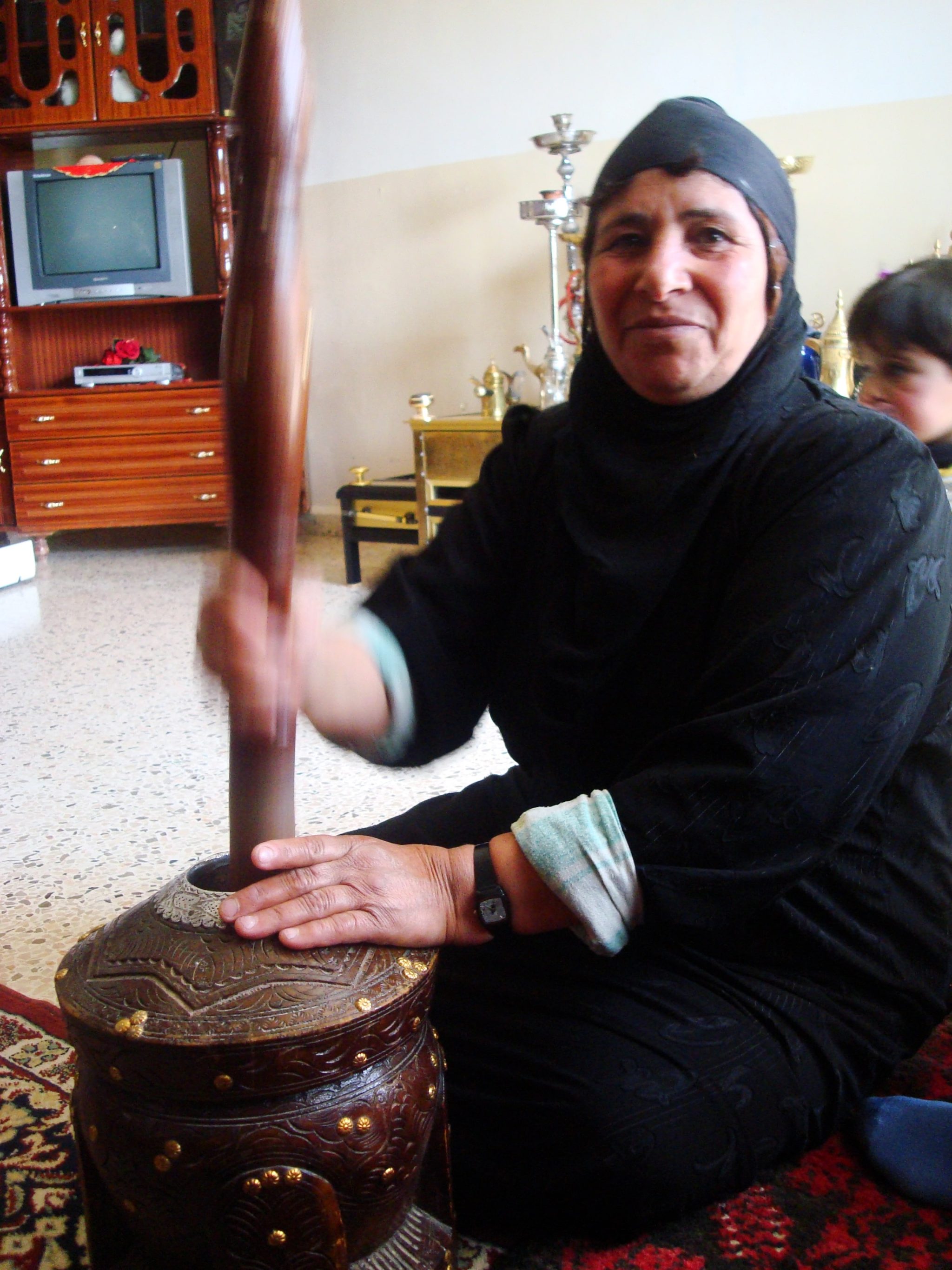 A Bedouin woman beating coffee beans at home.