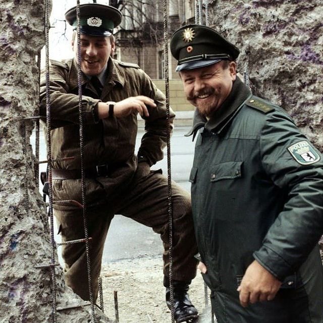 A border guard of the German Democratic Republic and a policeman of the Federal Republic of Germany at the Berlin Wall 1990